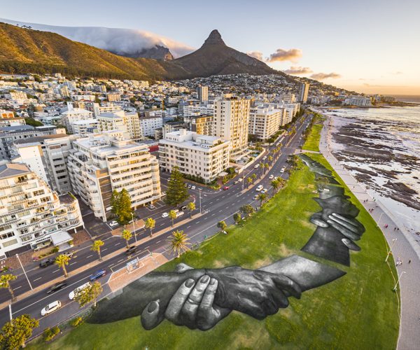 An aerial view shows a giant landart fresco by French-Swiss artist Saype, painted for the 9th step of his worldwide "Beyond Walls" project in Sea Point, Cape Town, South Africa, on Tuesday January 19, 2021. Three frescoes were created using approximately 1000 liters of biodegradable pigments made out of charcoal, chalk, water and milk proteins. The "Beyond Walls" project aims at creating the largest symbolic human chain around the world, promoting values such as togetherness, kindness and openness to the world. Here in Cape Town this step was motivated by the country's persisting need for reunification. Three frescoes representing widely different populations and realities within the city were created in Sea Point (6000 Sq. m), the Philippi township (800 Sq. m) and the Langa township (800 Sq. m). (Valentin Flauraud for Saype - EDITORIAL USE ONLY)